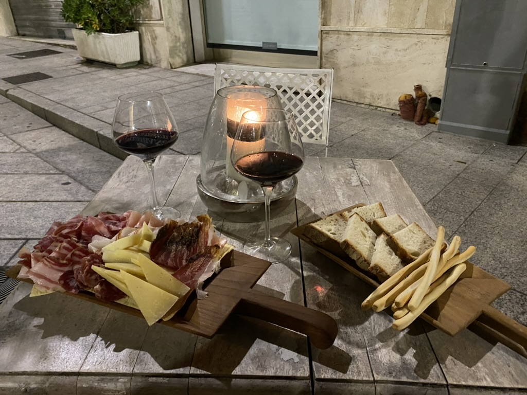 Vino, formaggi, salumi e pane serviti per un aperitivo nel centro di Olbia